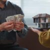Businessman counting us dollar banknotes and architect holding a model house