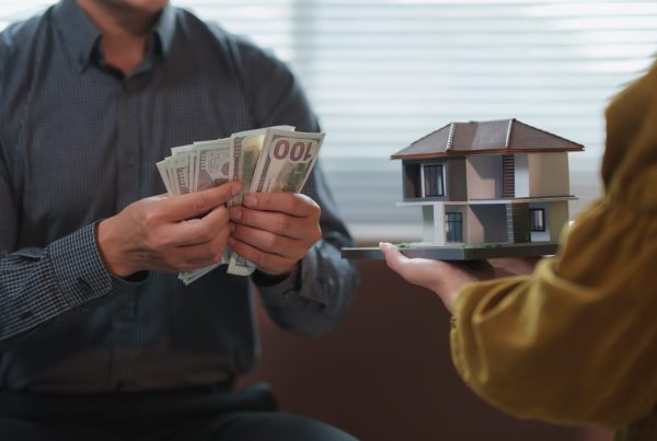 Businessman counting us dollar banknotes and architect holding a model house
