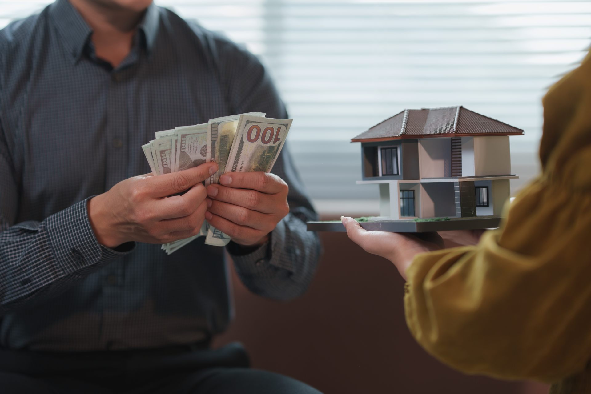 Businessman counting us dollar banknotes and architect holding a model house
